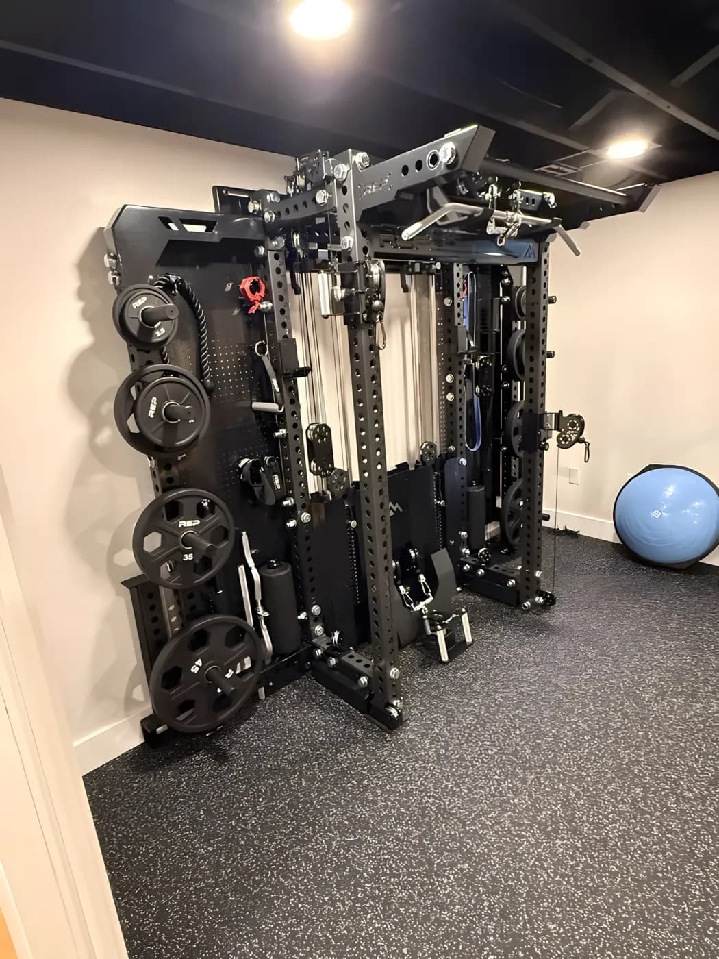 Basement gym wall with room for a full cable rack, under a black open ceiling