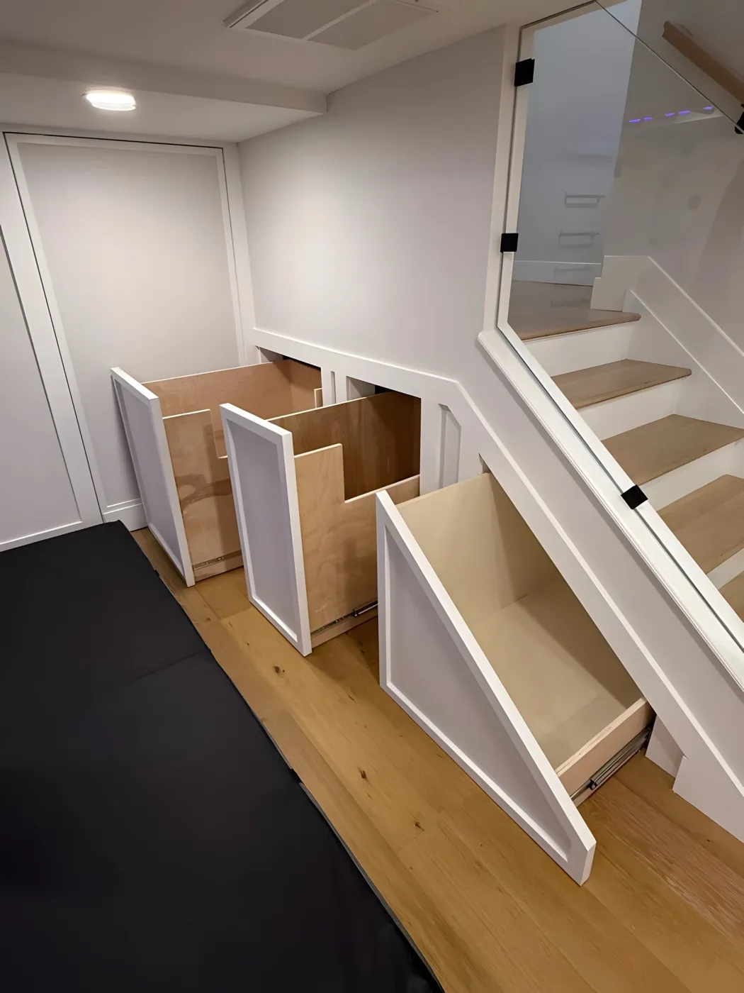 Three pull-out storage drawers built into the space under the basement stairs