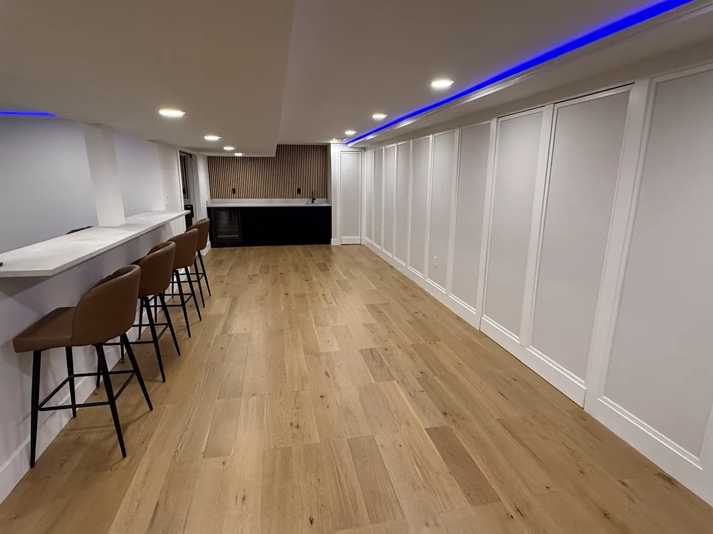 Finished basement bar with counter seating, paneled walls and cove lighting