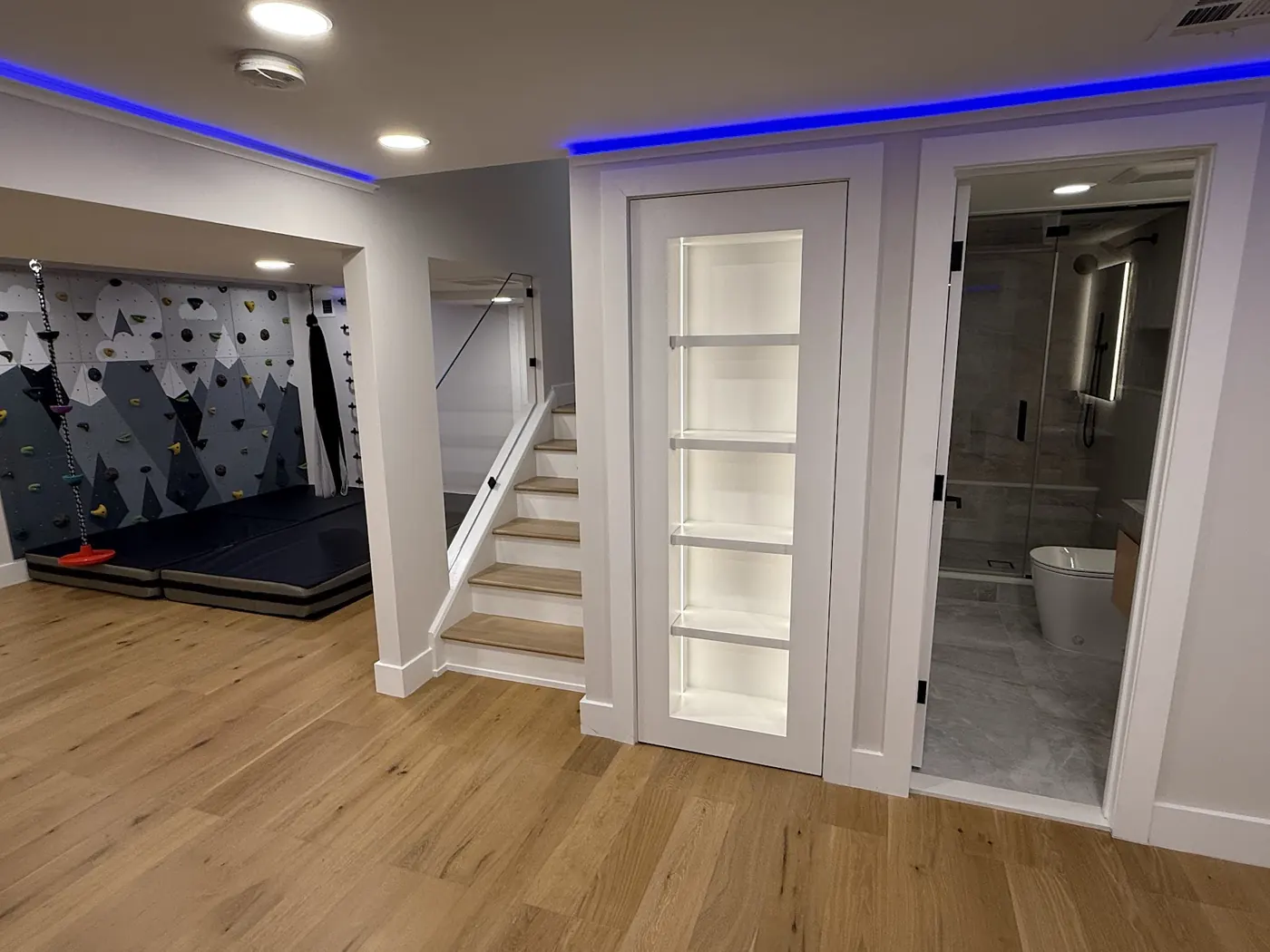 Finished basement staircase beside a children's climbing wall and play area