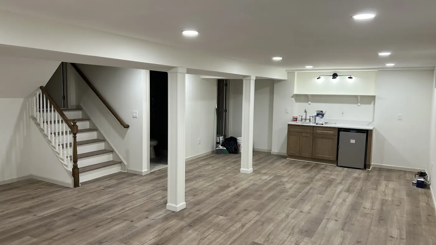 Finished basement with a staircase, wet bar area and wood-look flooring