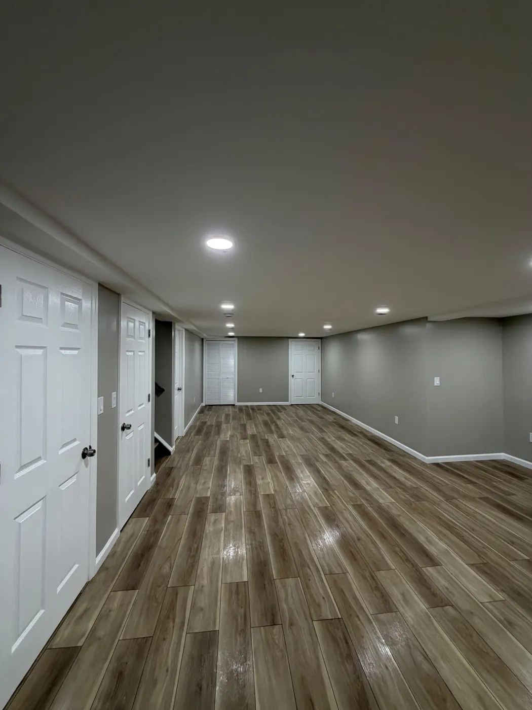 Finished basement in Woodbridge, NJ with wood-look tile flooring and recessed LED lighting