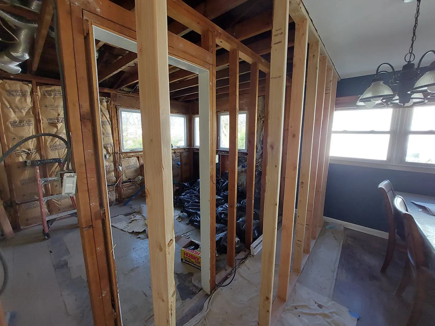 Kitchen remodel in progress, with an interior wall opened down to its wood studs next to the dining area