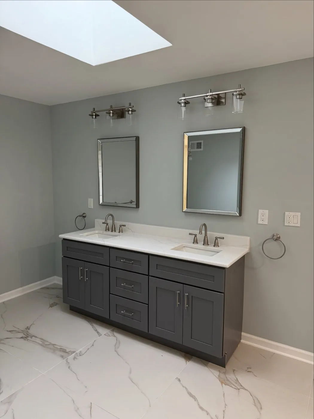 Gray double vanity with a white quartz top, two mirrors and a light over each sink