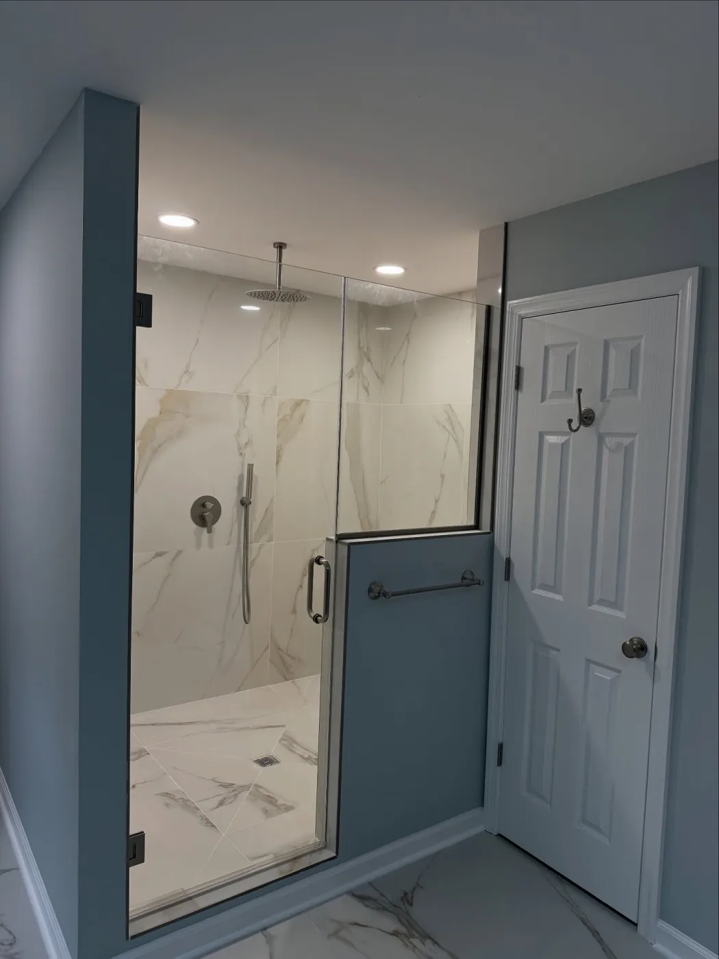 Walk-in shower with a half wall holding a towel bar and clear glass above it