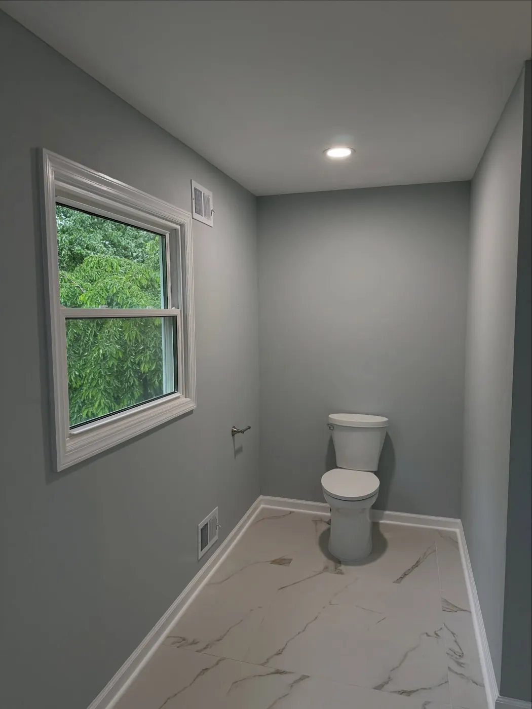 Toilet in its own corner of the bathroom next to a window