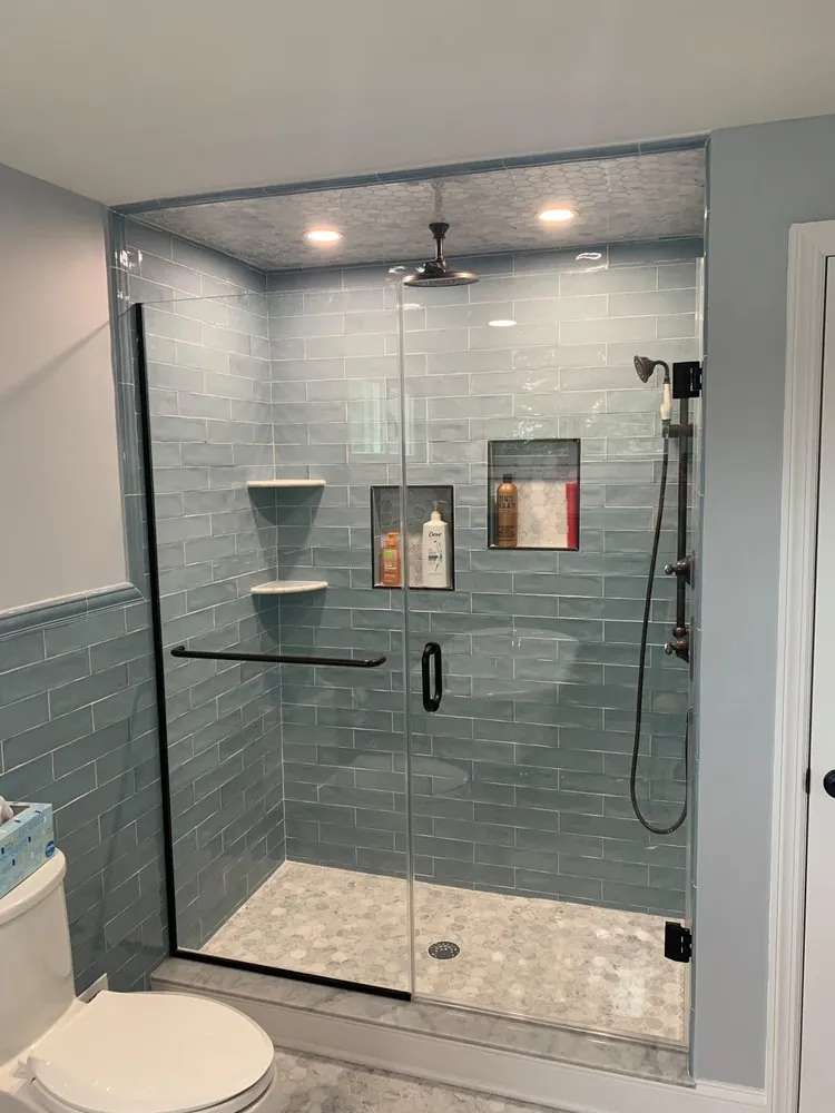 Shower with blue-gray subway tile, marble hexagon floor and ceiling, two niches and oil-rubbed bronze fixtures.