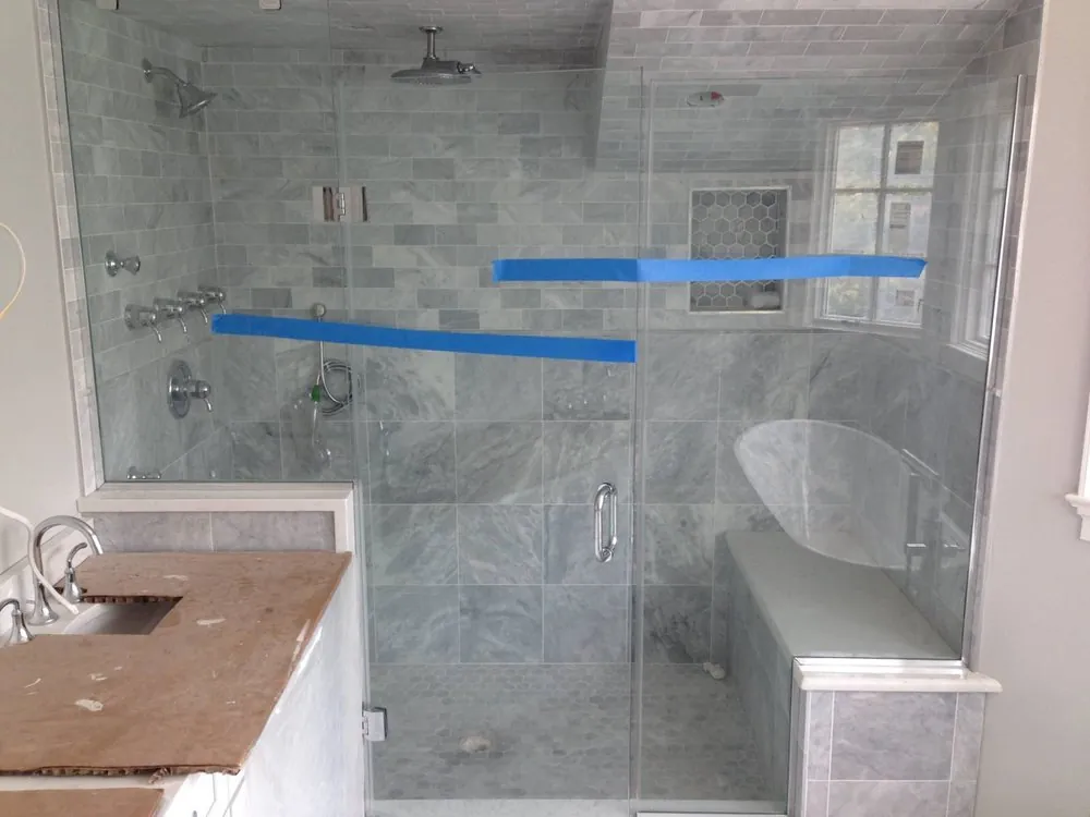 Glass shower with gray marble subway and large tile, hex floor, bench, body sprays and a vanity still under cardboard.