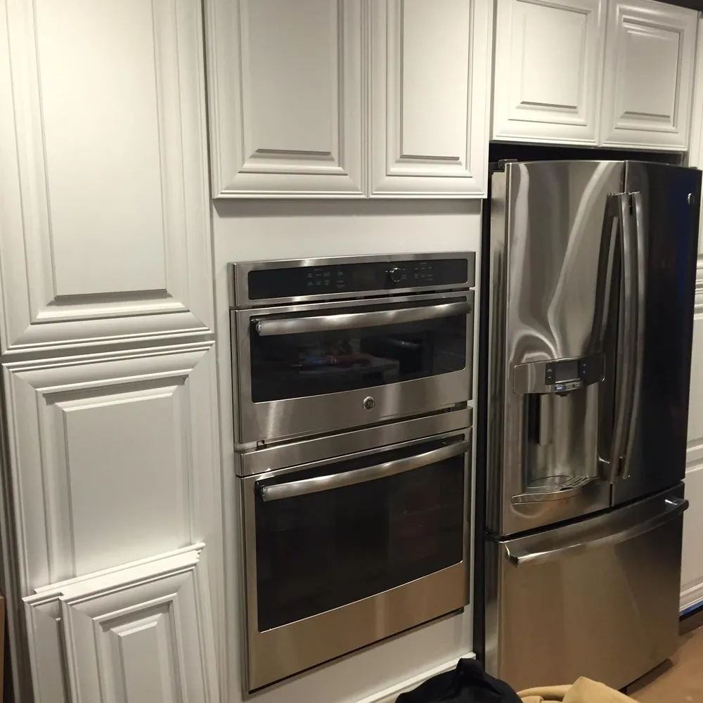 Stainless double wall oven and French-door fridge set into white raised-panel cabinets.