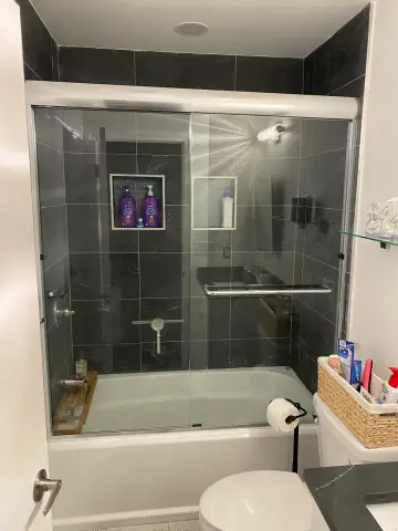Dark tile tub shower with glass doors