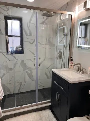 Small bathroom with glass shower and navy vanity